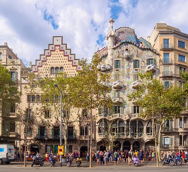 Passeig de Gràcia con Casa Amatller e Casa Batlló affiancate sotto un cielo azzurro, con i platani in primo piano