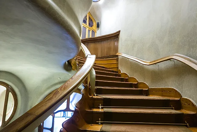 The curved wooden staircase of Casa Batlló winding upward along the smooth, rounded wall
