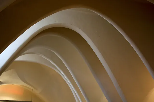 Gli archi parabolici bianchi della soffitta di Casa Batlló, una fila di volte lisce a catenaria simili alla gabbia toracica di un animale